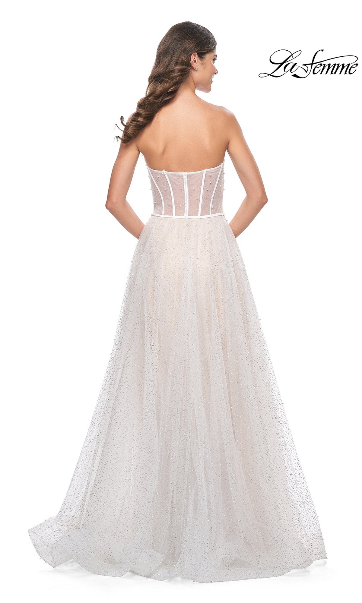 A woman wears the La Femme Strapless Long White Prom Dress 32149, featuring a sheer corset bodice, flowing skirt, and subtle sparkle detailing for an elegant formal look; shown from the back.